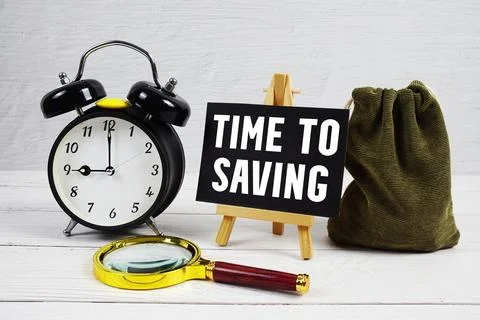 Time To Saving text with alarm clock and magnifying glass on wooden backgroun 写真素材