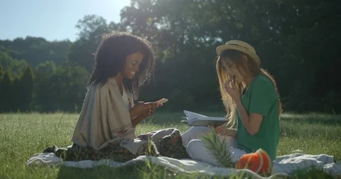 Time-spending of two beautiful multi-ethnic girlfriends on a picnic. Smiling Stock Footage 84640319