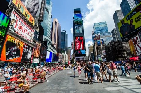 Time square in day time with chairs of the coffee shop and people standing Stock Photos