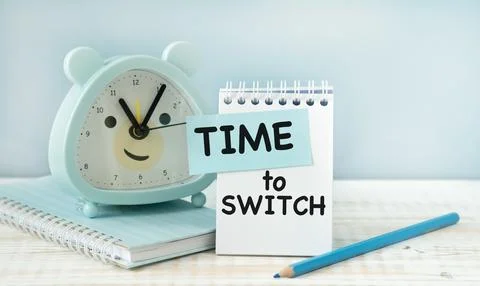 Time To Switch text on alarm clock on wooden table indoors. Stock Photos