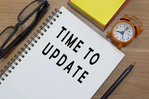 Time to update text on notepad with alarm clock on wooden desk. Business conc 库存照片