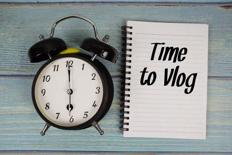 Time to Vlog text written on notepad with alarm clock on wooden background Stock Photos