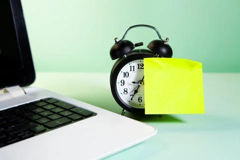 Time for a work. a alarm clock and a notebook on a yellow background. Foto stock