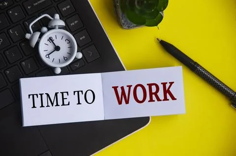 Time to work text on notepad with alarm clock and laptop background. Workin.. Stock Photos