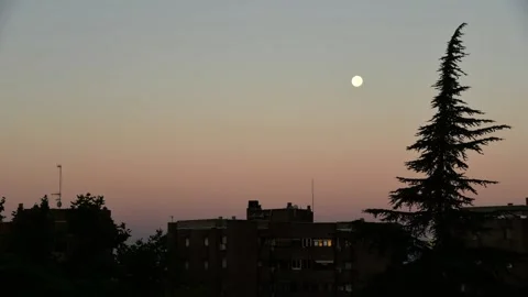 Timel-apse of moon moving over city at sunrise Stock Footage 138599145
