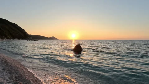 Timelaps. Quick shot. Sunset against the sea. A rock in the sea at sunset. Stock Footage 329537601