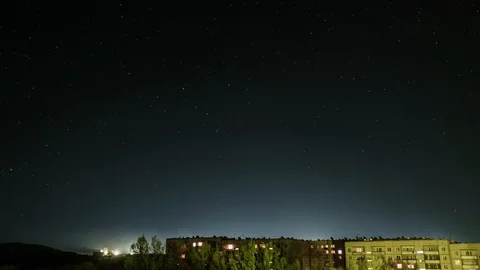 TimeLaps of the starry sky against the background of a houses, in the windows of Stock Footage