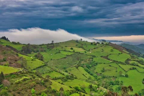 Timelapse 4K mists drift up a hill of green meadows during a sunset Stock Footage 153966102