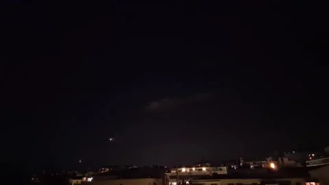 Timelapse of an airplane flying at night over the rooftops of a city Stock Footage 327678301