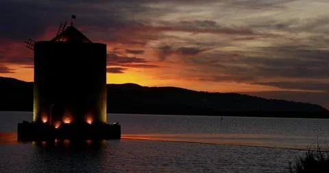 Timelapse  An ancient windmill with romantic lights on the sea bay at sunset Stock Footage 104517640