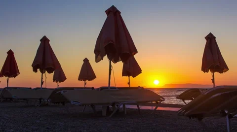 Timelapse Beautiful sunset on the beach. silhouettes disclosed umbrellas and Stock Footage 65582054
