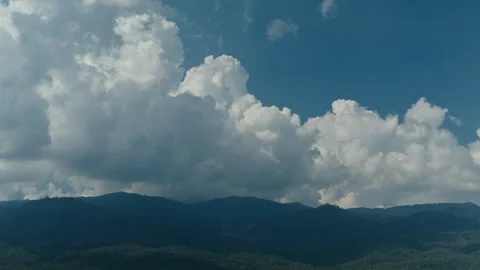 Timelapse of big cumulus clouds moving in the blue sky above the hills Video stock 261490909