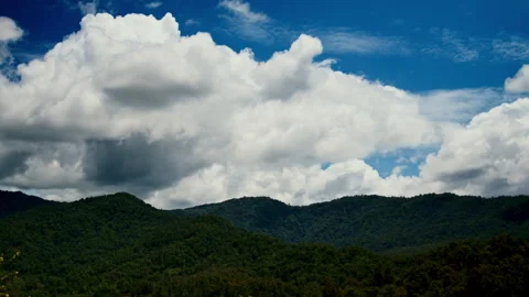 Timelapse of the big white clouds moving in the blue sky above the green hills Stockbeeldmateriaal 261493118