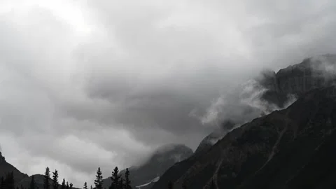 Timelapse of blowing white and grey storm clouds moving between mountains above  Stock Footage 303380007