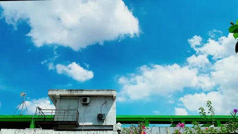 Timelapse of blue sky and moving clouds above an apartment rooftop Stock Footage 330571987
