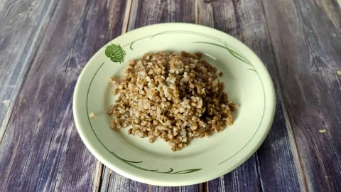 Timelapse of boiled buckwheat in a white plate on a wooden table Stock Footage 231593957