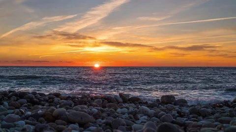 Timelapse of bright orange sun setting into the Black Sea. Sunset on a pebble Stock Footage 80267231