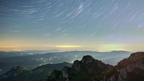 Timelapse of bright star trails over a mountain landscape illuminated by the Stock-Footage 316140119