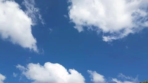 Timelapse of bright white cumulus clouds passing across a vivid blue sky on a Vídeos de archivo 347926343