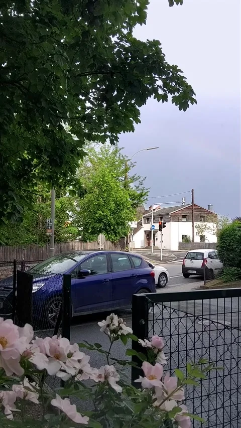 Timelapse of a car at an intersection and a rainbow in the sky after rain Stock Footage 243009946