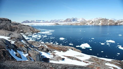 Timelapse of chunks of ice moving and melting across lake under mountains Stock Footage 124239553