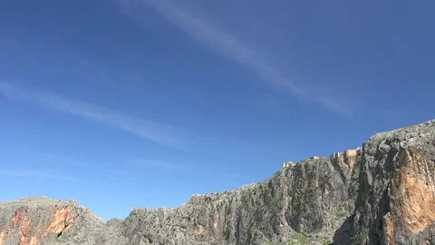 Timelapse cirrus clouds drift above treeless rocky mountain range forming a Stock Footage 339563110