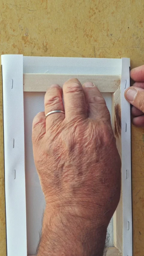 Timelapse close up shot of a mans hands stretching and stapling a canvas prin Vídeo Stock 205440620