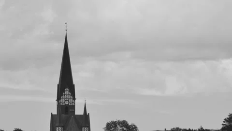 Timelapse of cloud movement over an old medieval church with a clock, in bla Vídeos de archivo 255480356