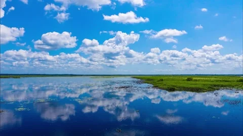 Timelapse clouds across blue sky reflecting on water 库存影片 342994970