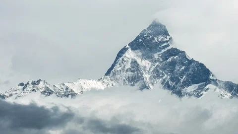 Timelapse of clouds and fog rolling over snow covered mountains on cloudy day Stock Footage 124237866