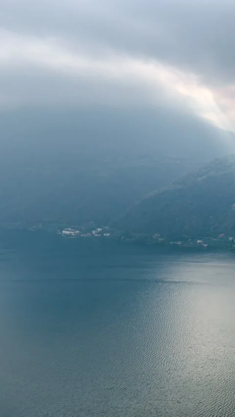 Timelapse of Clouds and Sun Rays Over Calm Lake and Hillside Landscape Stock Footage 340141032