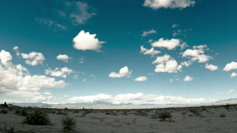 Timelapse clouds cross blue sky in front of mountains in the Mojave 스톡 동영상 230062454