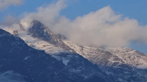 Timelapse of clouds drifting over snowy mountain peaks Video stock 317821582