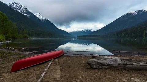 Timelapse of clouds flowing over mountain lake from sandy shore with canoe Stock Footage 50589135