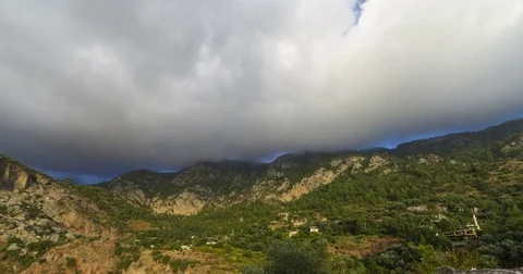 Timelapse of Clouds Hitting a Hill Peak over a Turkish Village and Forest View	 Stock Footage 74558627