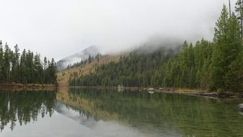 Timelapse of clouds on a misty morning over a lake, Teton National Park. Stock Footage 75065162