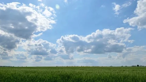 Timelapse. Clouds move quickly across the blue sky over a green fields Stock Footage 198232553