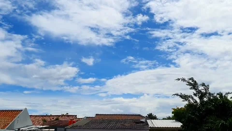 Timelapse of clouds moving above the rooftops of houses, creating a dynamic.. Stock Footage 301063030