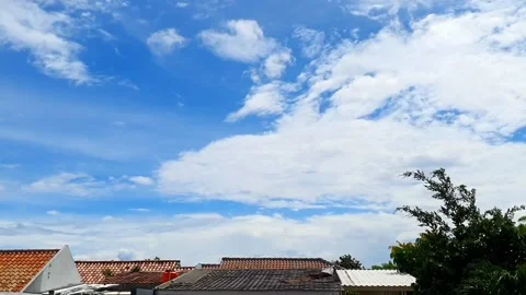 Timelapse of clouds moving above the rooftops of houses, creating a dynamic.. Stock Footage 301063123