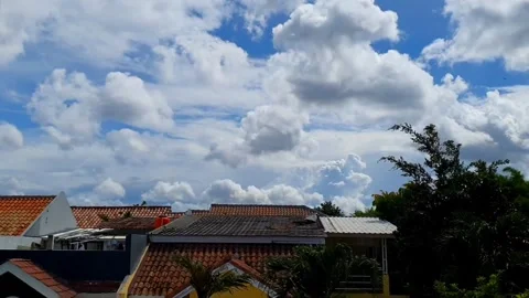 Timelapse of clouds moving above the rooftops of houses, creating a dynamic.. Stock Footage 301063260