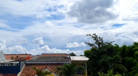 Timelapse of clouds moving above the rooftops of houses, creating a dynamic.. Stock Footage 301063522