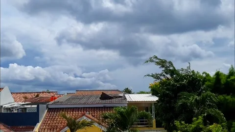 Timelapse of clouds moving above the rooftops of houses, creating a dynamic.. Stock Footage 301063526