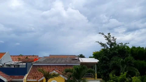 Timelapse of clouds moving above the rooftops of houses, creating a dynamic.. Stock Footage 301063935