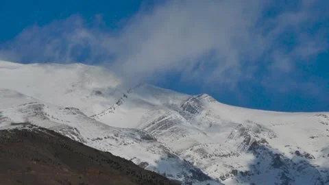 Timelapse of clouds moving across snow-covered mountain ridges under a blue sky Stock Footage 318922030