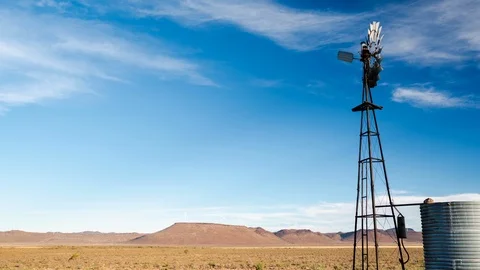 Timelapse of clouds moving behind a windmill in a field Stock Footage 101683711