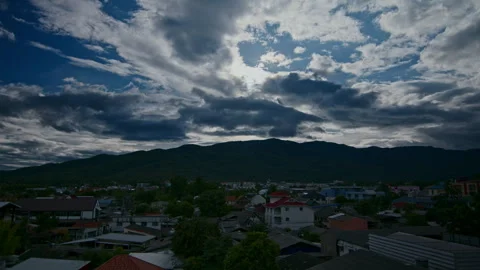 Timelapse of the clouds moving in the dark blue sky above the city and hills Stock Footage 261493683