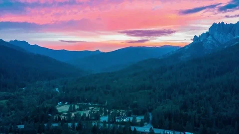 Timelapse of clouds moving over grassy landscape with mountains during sunset Stock Footage 94839130