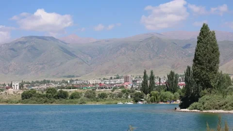 Timelapse of Clouds Over City with Mountain Backdrop and Lakeside Recreation Stock Footage 344733349