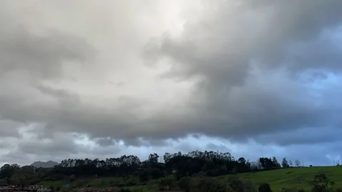 Timelapse of clouds over green hills with trees against blue sky and grey clouds 스톡 동영상 304145749