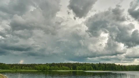 A timelapse of clouds over the lake and forest. Stormy and rainy gray clouds Stock Footage 293009083
